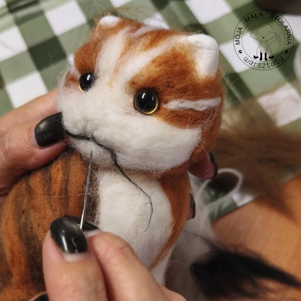Pani filcuje na sucho z wełny czesankowej, robi rudego filcowanego kotka o bursztynowych oczach.